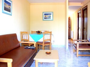 Un comedor con una mesa dispuesta para cuatro personas, un sofá marrón y una mesita con un cuenco.