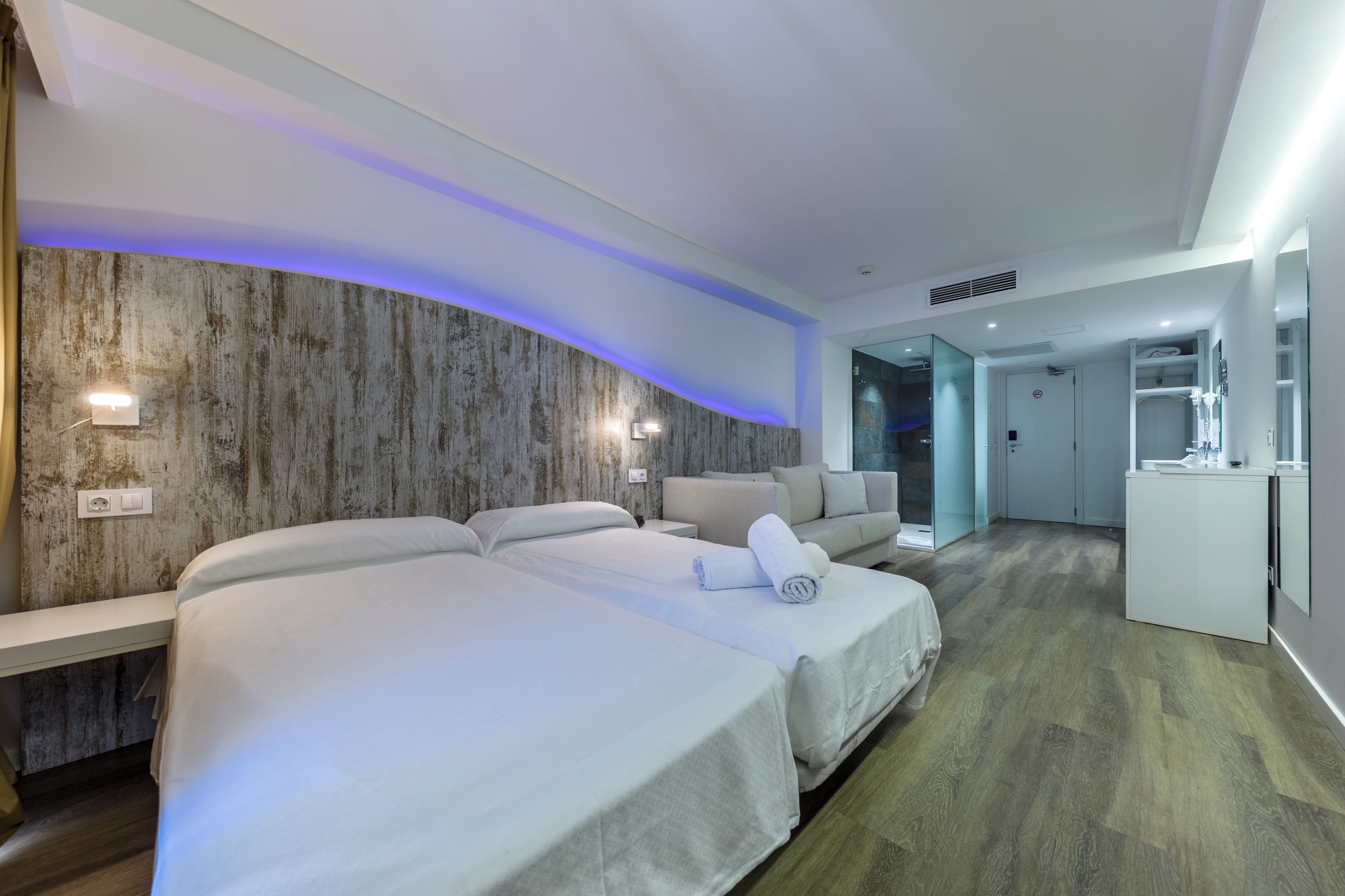 Una camera d'albergo moderna con un letto grande, un divano e una scrivania.