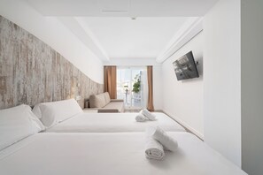 A hotel room with two beds, a sofa, a TV, and a view of the outside. - Welikehotel Triton Beach (Capdepera)