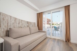 Una sala moderna con un sofá, una pared decorativa de madera y vistas a una zona de estar exterior a través de un ventanal.