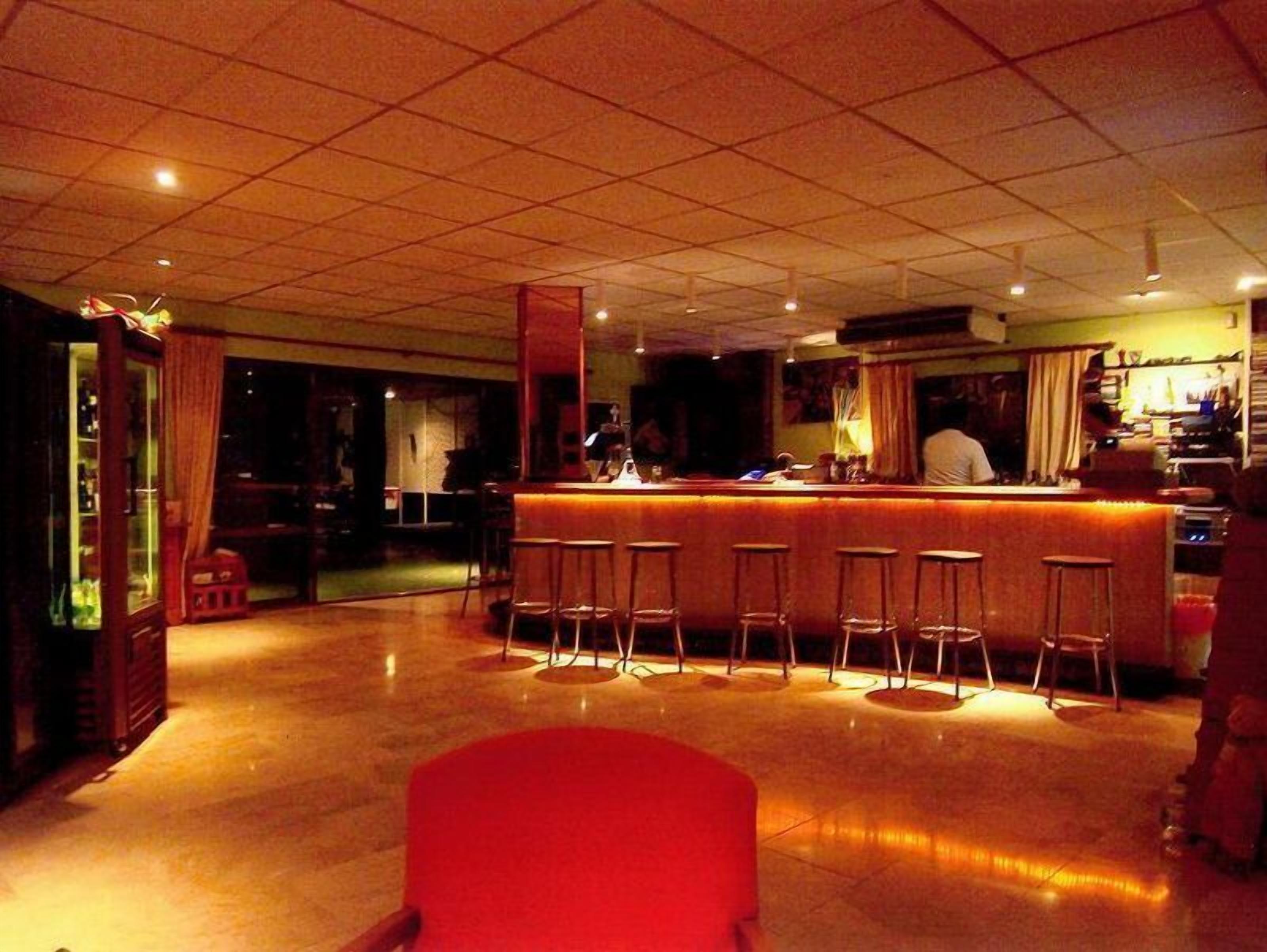 Zona de bar con taburetes, una barra y una cocina al fondo.