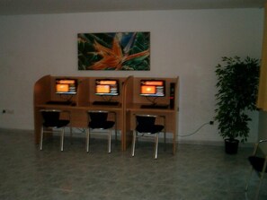 Una habitación con un escritorio de madera y tres monitores de computadora, una planta en maceta y un cuadro en la pared.