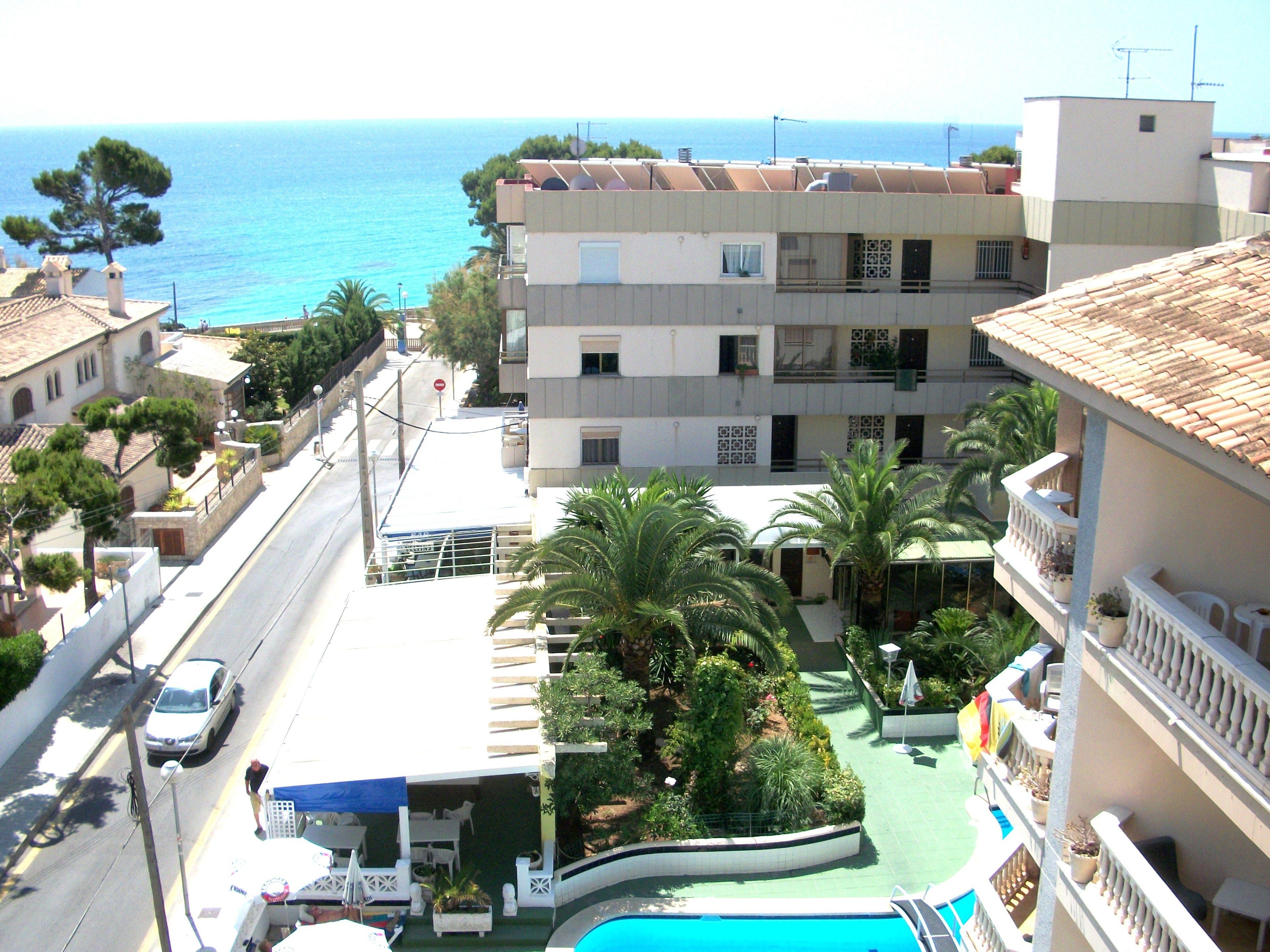 Un albergo con piscina, vista sul mare e una strada con auto.
