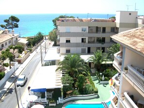 A hotel with a pool, a view of the sea, and a street with cars. - Welikehotel Triton Beach (Capdepera)