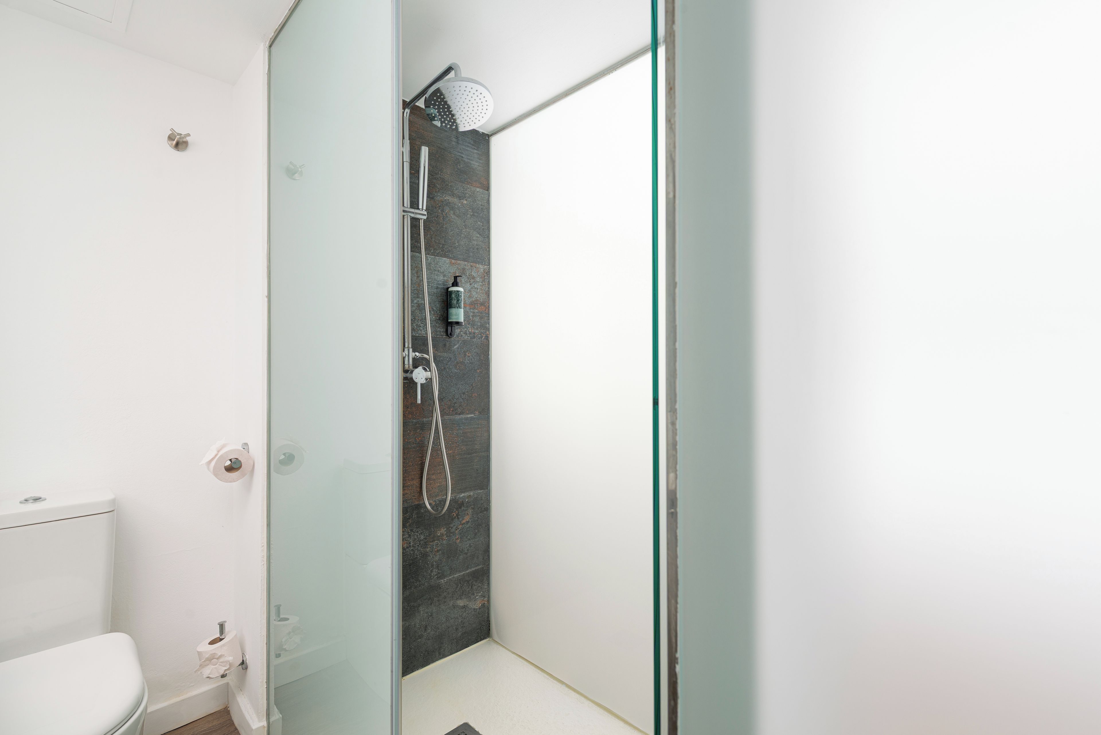 Un baño moderno con cabina de ducha de vidrio, inodoro y ducha visible.