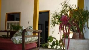 Una habitación con un banco de madera, un sofá rojo y una planta en maceta con hojas largas.