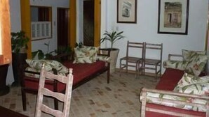 Una sala de estar con un sofá, dos sillones y una mesita de centro. Hay dos cuadros enmarcados en la pared.