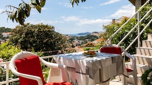Une table recouverte d’une nappe, deux chaises rouges et une assiette de fruits.