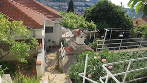 Un quartier résidentiel caractérisé par des toits recouverts de tuiles en terre cuite, des plantes en pot et une balustrade métallique blanche.