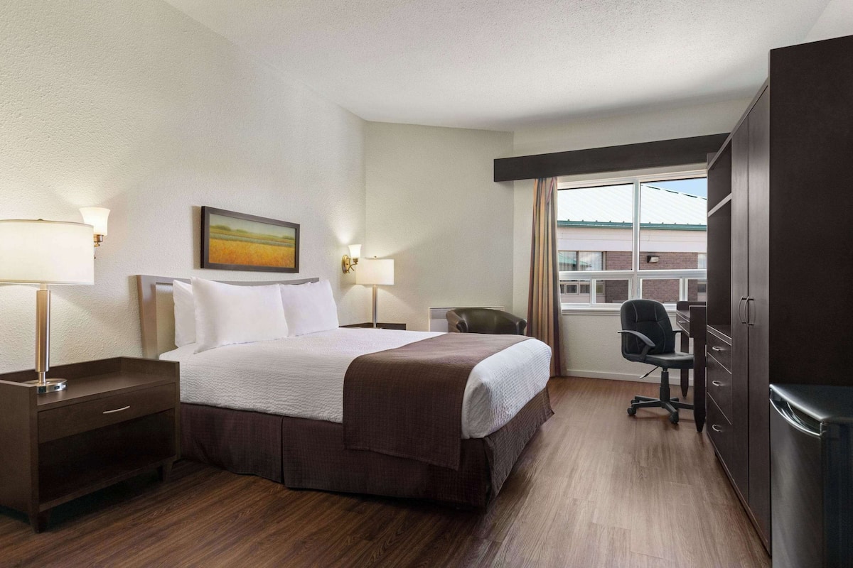 Una habitación de hotel con cama, mesitas de noche, escritorio, silla y armario.
