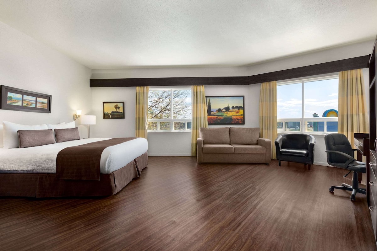 Habitación de hotel con una cama grande, un sofá, un escritorio con una silla y una ventana con vistas al paisaje.