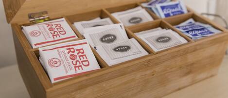 Una caja de madera con compartimentos que contienen varios paquetes etiquetados como 'Red Rose' y 'Sucre'.