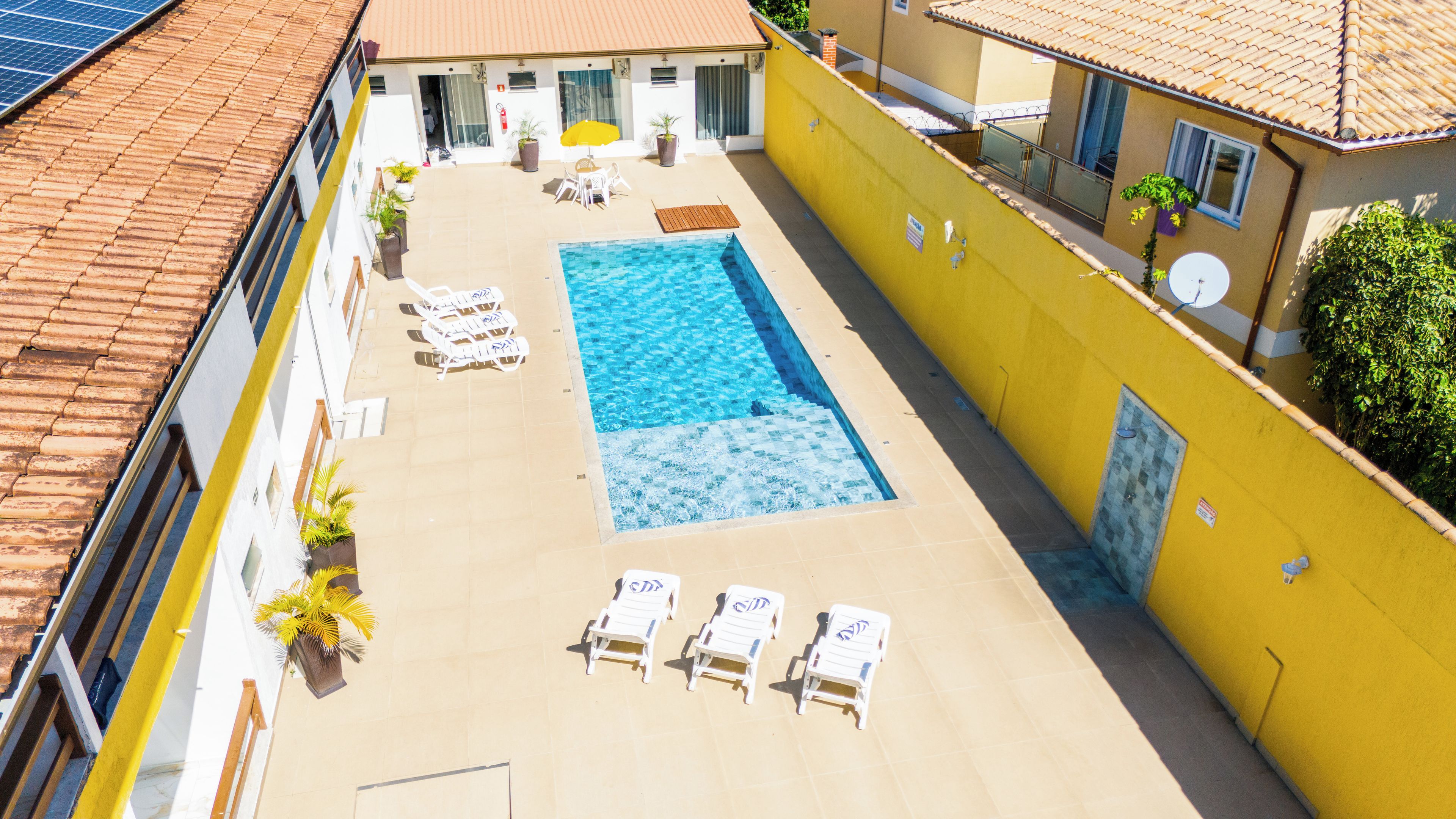 Una piscina en la azotea con sillones de descanso y plantas en macetas.