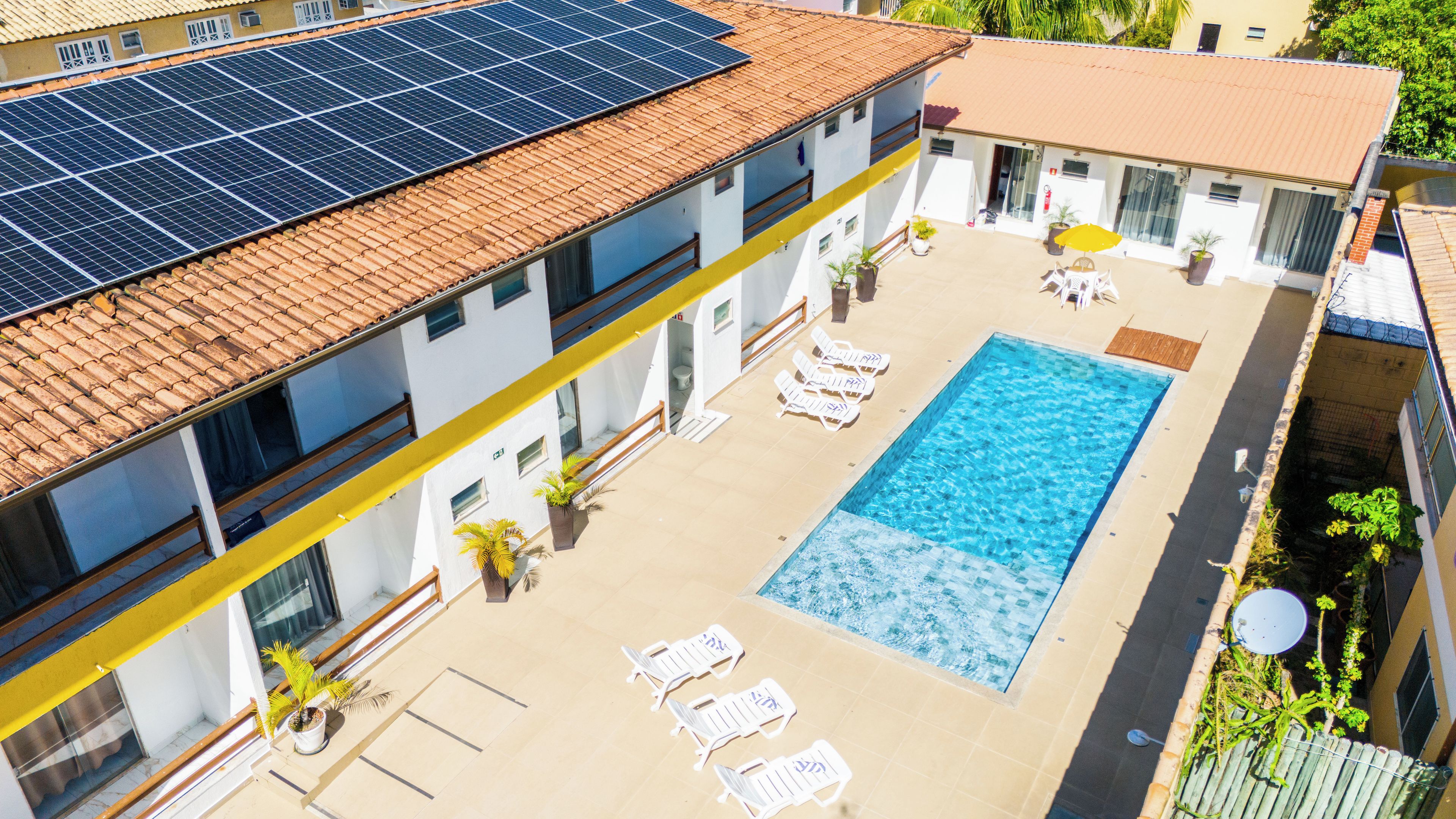 Terraço com painéis solares, piscina e cadeiras de descanso.