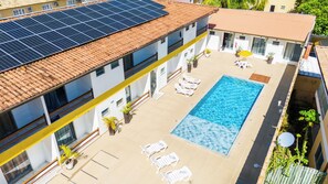Una azotea con paneles solares, una piscina y sillones de descanso.