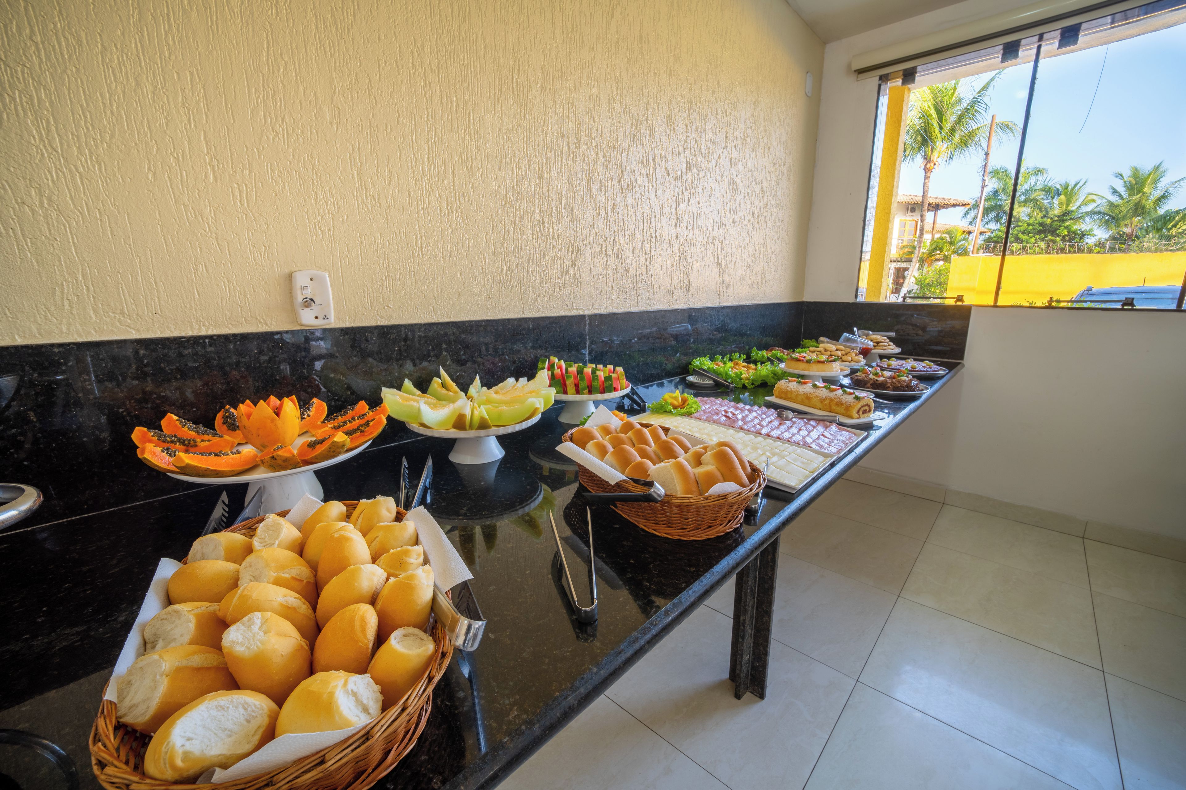 A buffet with various food items including bread, fruits, and salads.