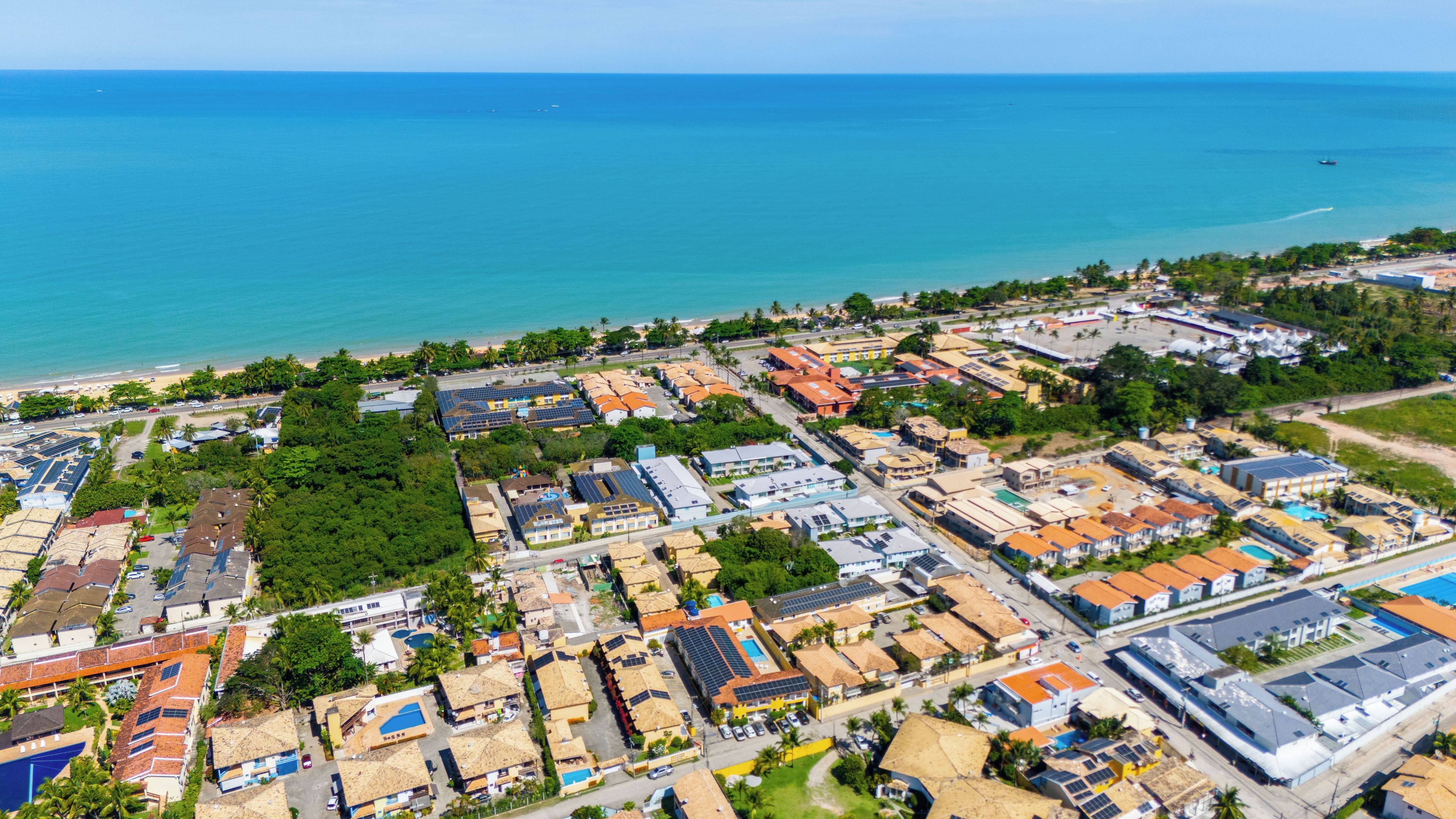 Vista aérea de una zona residencial costera con casas, caminos y una playa.
