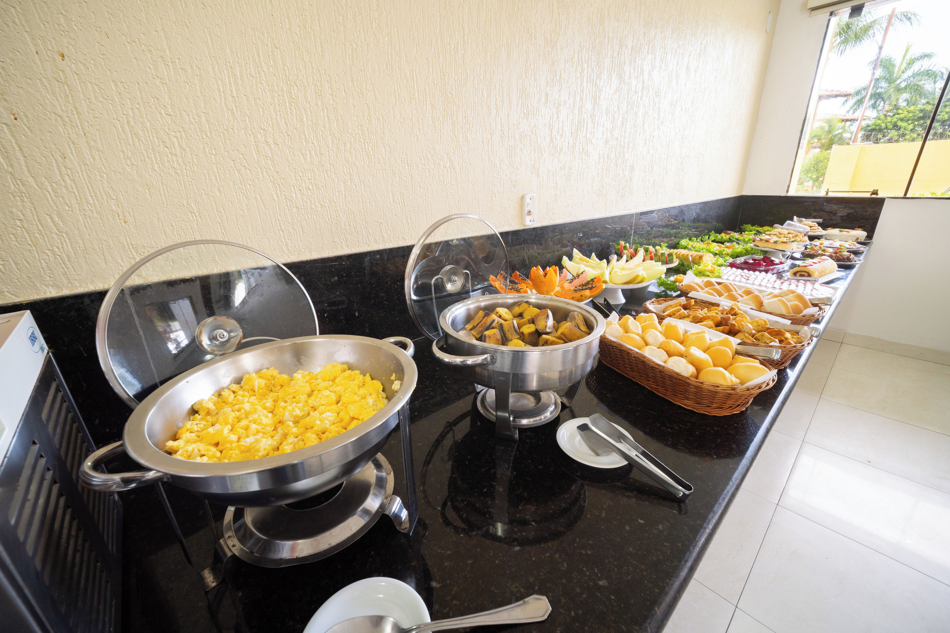 Ein Buffet mit verschiedenen Speisen, darunter Rührei, Früchte und Gebäck.