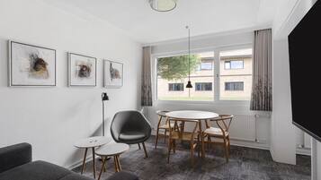 A modern room with a round table, chairs, a sofa, and artwork on the wall.