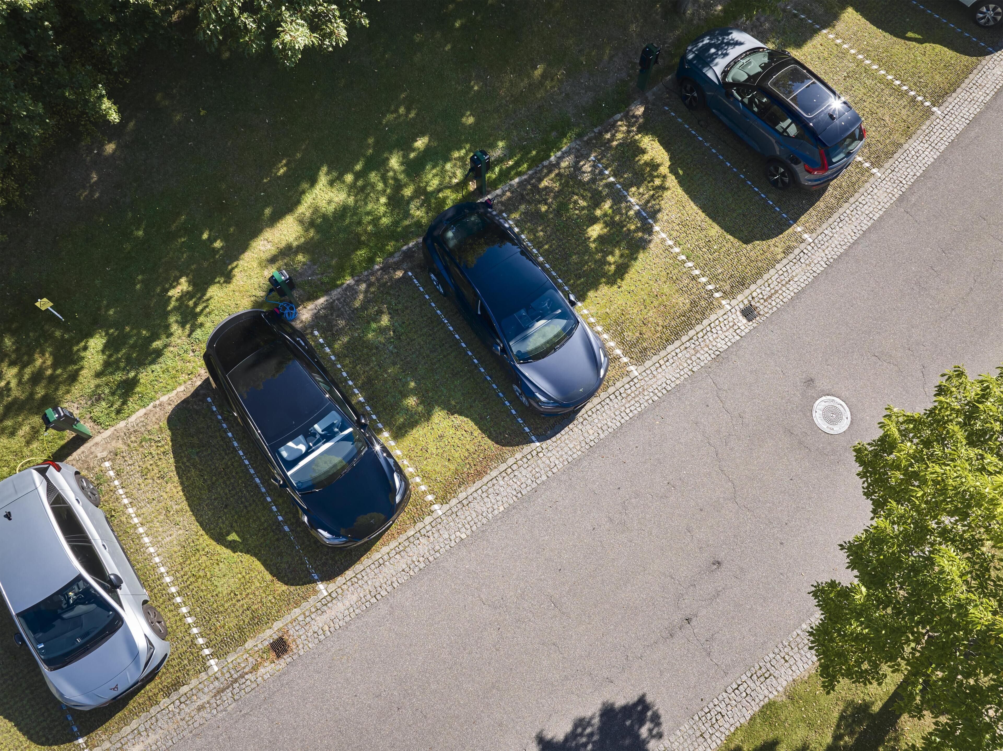 Vista aérea de un estacionamiento con tres coches aparcados en fila.