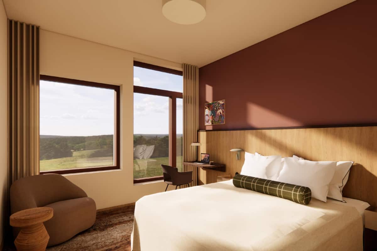 Ein Hotelzimmer mit Bett, Schreibtisch, Stuhl und Blick ins Freie.