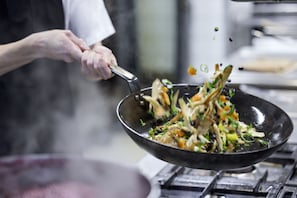 Un cocinero lanzando comida en un wok.