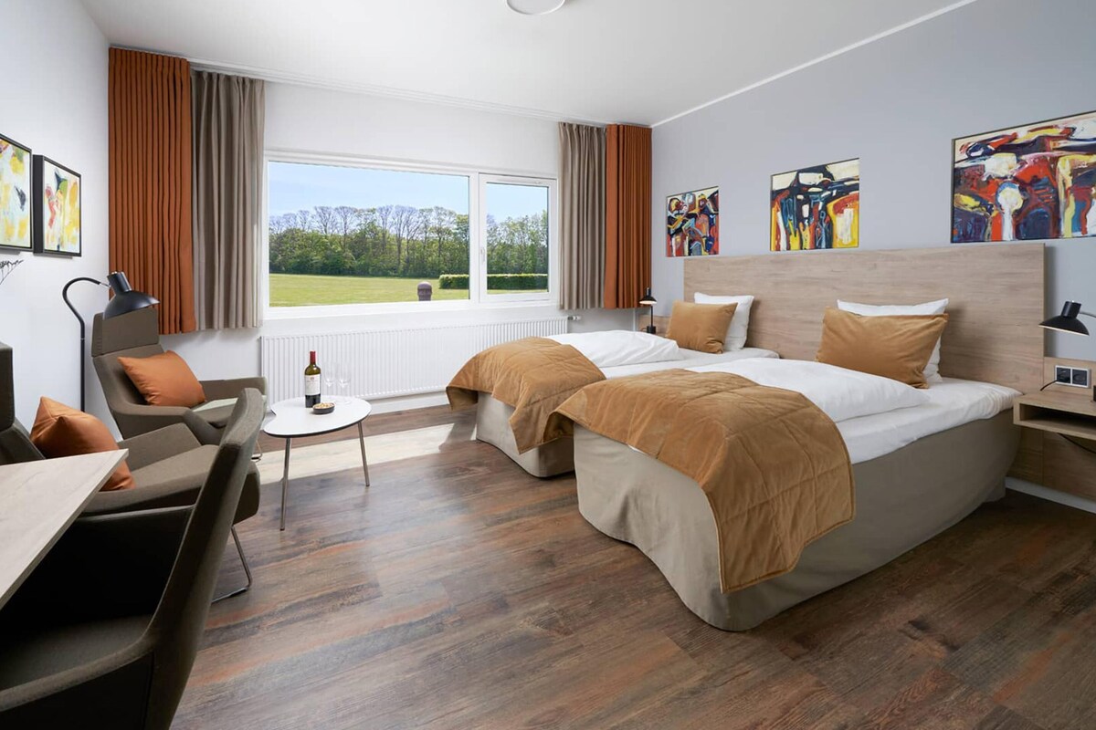 Habitación de hotel con una cama grande, un escritorio, una silla y vistas al exterior.