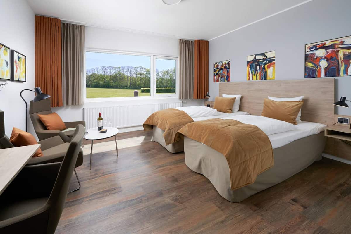 Ein Hotelzimmer mit einem großen Bett, einem Schreibtisch, einem Stuhl und Blick ins Freie.