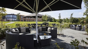 An outdoor seating area with wicker furniture and a large umbrella. - Trinity Hotel og Konference, BW Signature Collection (Fredericia)
