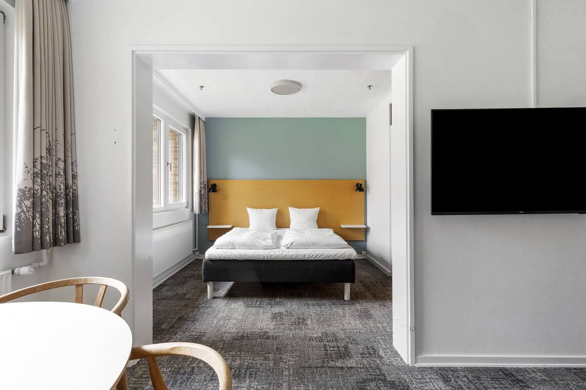 Ein Hotelzimmer mit Bett, Fernseher, Fenster und Tür.