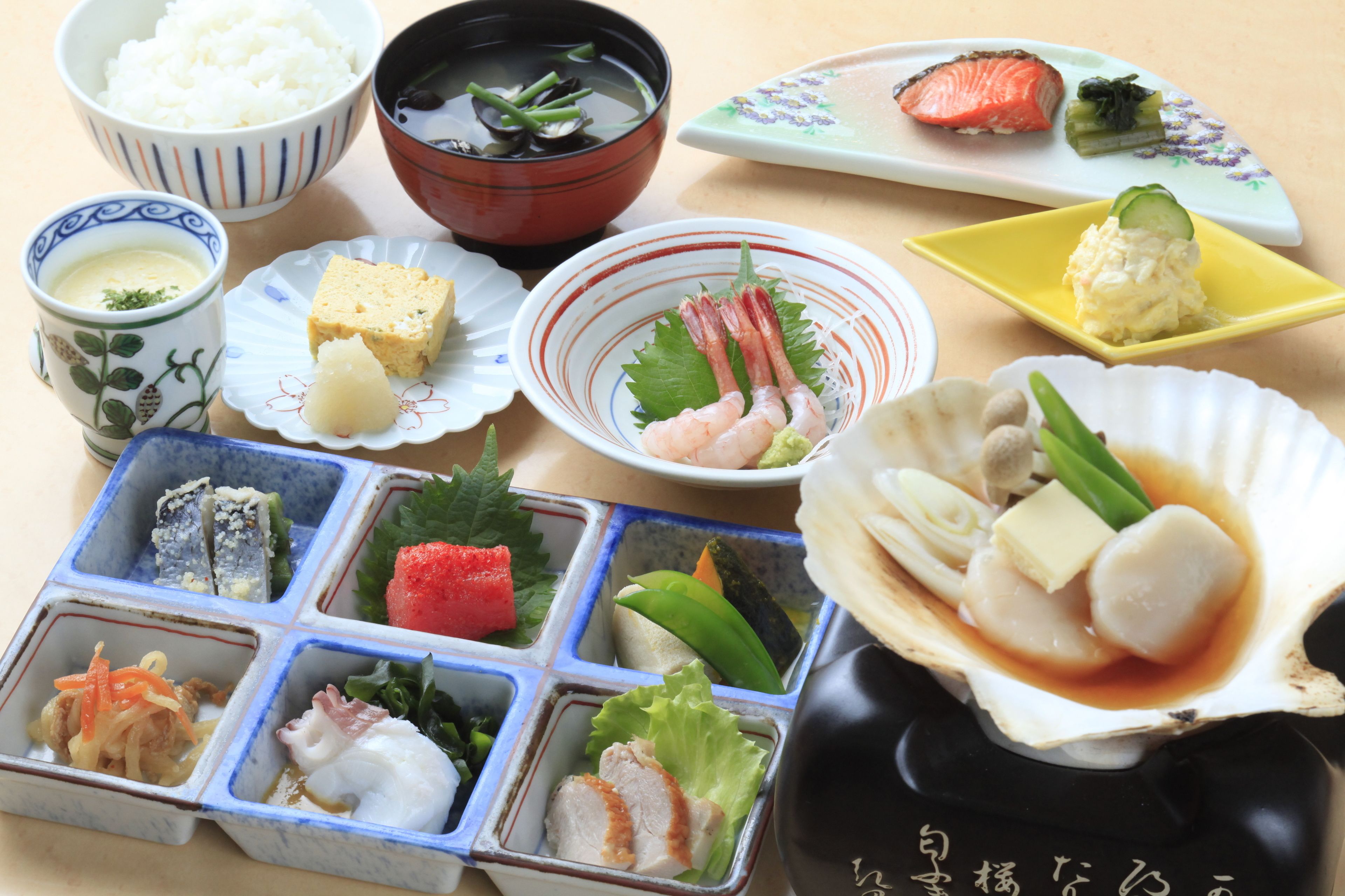 A variety of Japanese dishes including sushi, sashimi, and tempura, served on multiple plates and bowls.