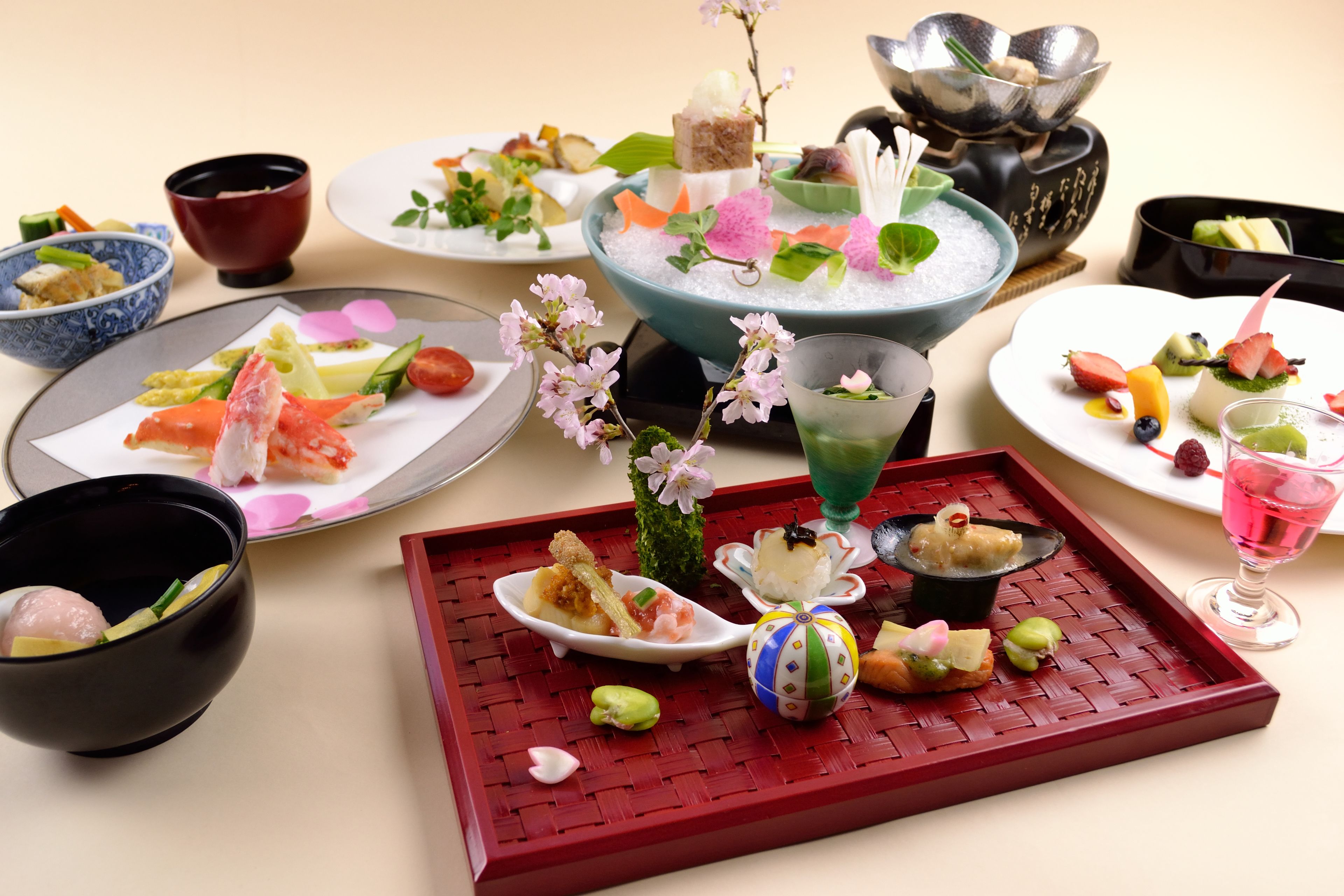 A variety of dishes and drinks arranged on a table, including sushi, fruit, and a decorative centerpiece.