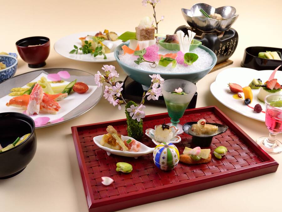Eine Auswahl an Speisen und Getränken auf einem Tisch, darunter Sushi, Obst und ein dekorativer Mittelpunkt.