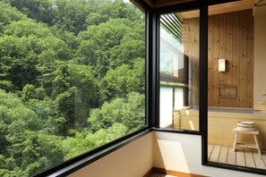 Una habitación con un ventanal que da a un bosque frondoso.