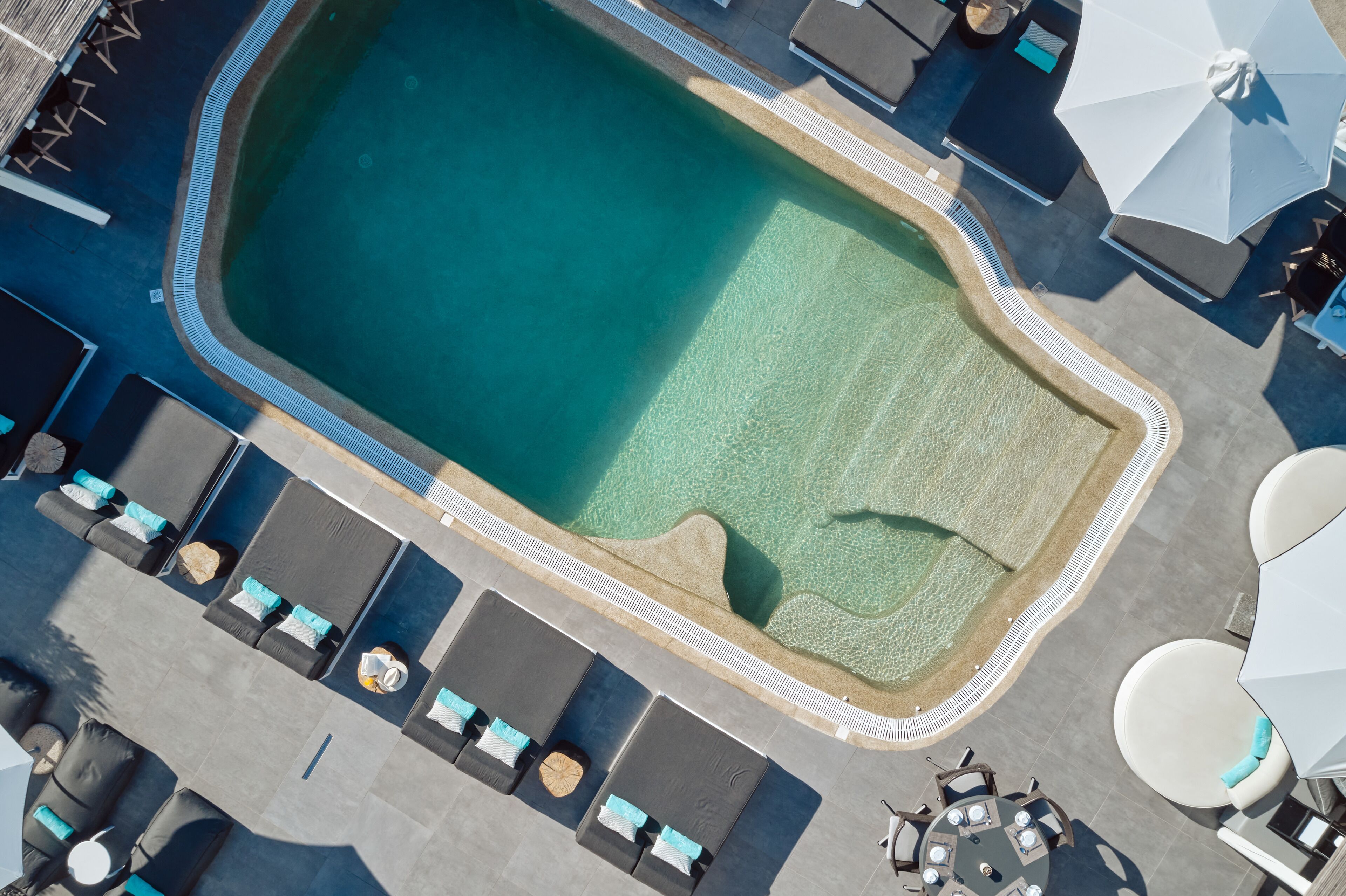 Vue aérienne d’une piscine avec des chaises longues et des parasols.