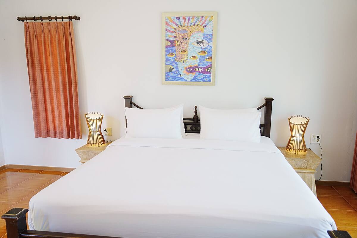 Un lit bien fait, avec du linge de lit blanc, une décoration murale et deux lampes de chevet.