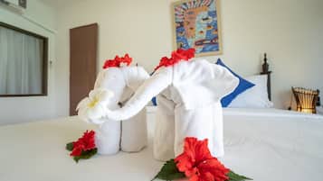 A hotel room with a bed, a painting on the wall, and a decorative towel elephant on the bed.