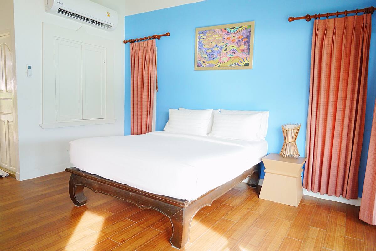Une chambre avec un lit en bois, une porte blanche et un mur bleu.