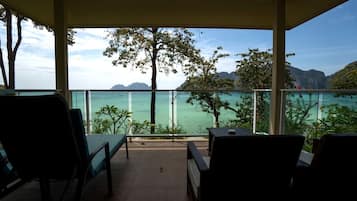 A balcony with a view of the sea and mountains, featuring two chairs and a table.