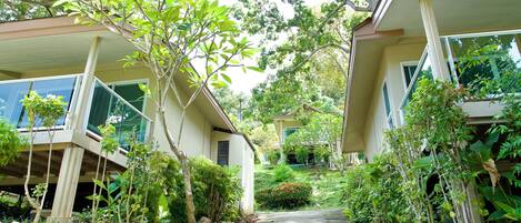 A residential area with two-story houses, a concrete pathway, and lush greenery.