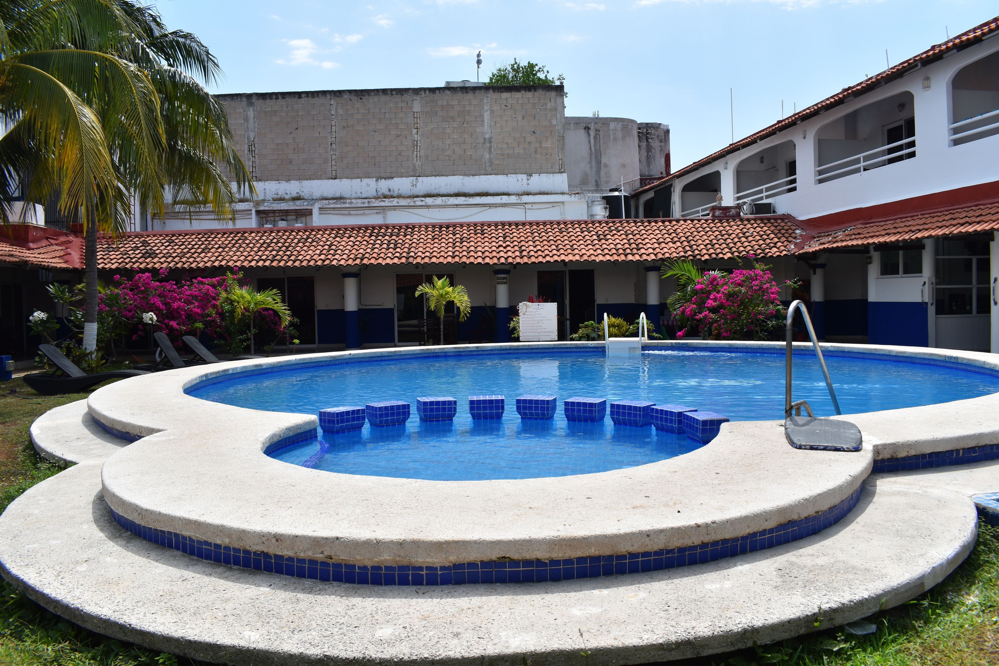 Piscina con borde de azulejos, rodeada por un suelo de hormigón.