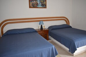 A bedroom with two beds, a nightstand with a lamp, and a painting on the wall.