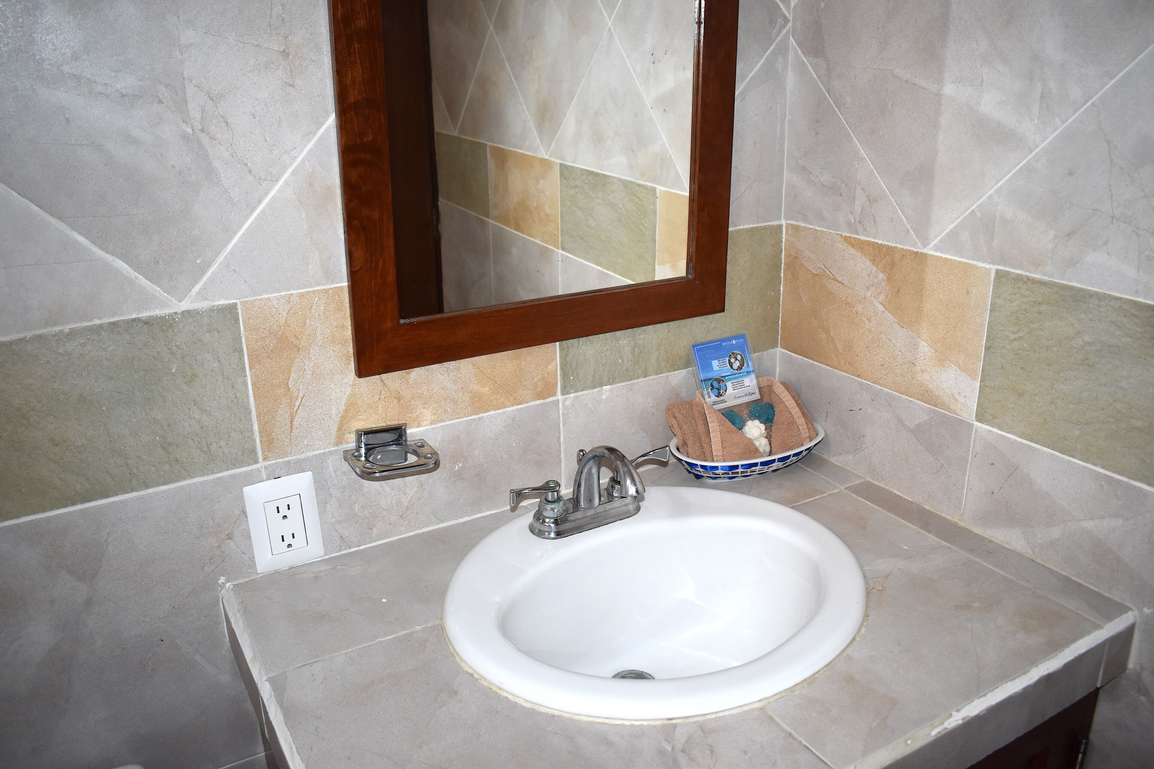 Une salle de bain avec un lavabo blanc, un miroir et un porte-serviettes.