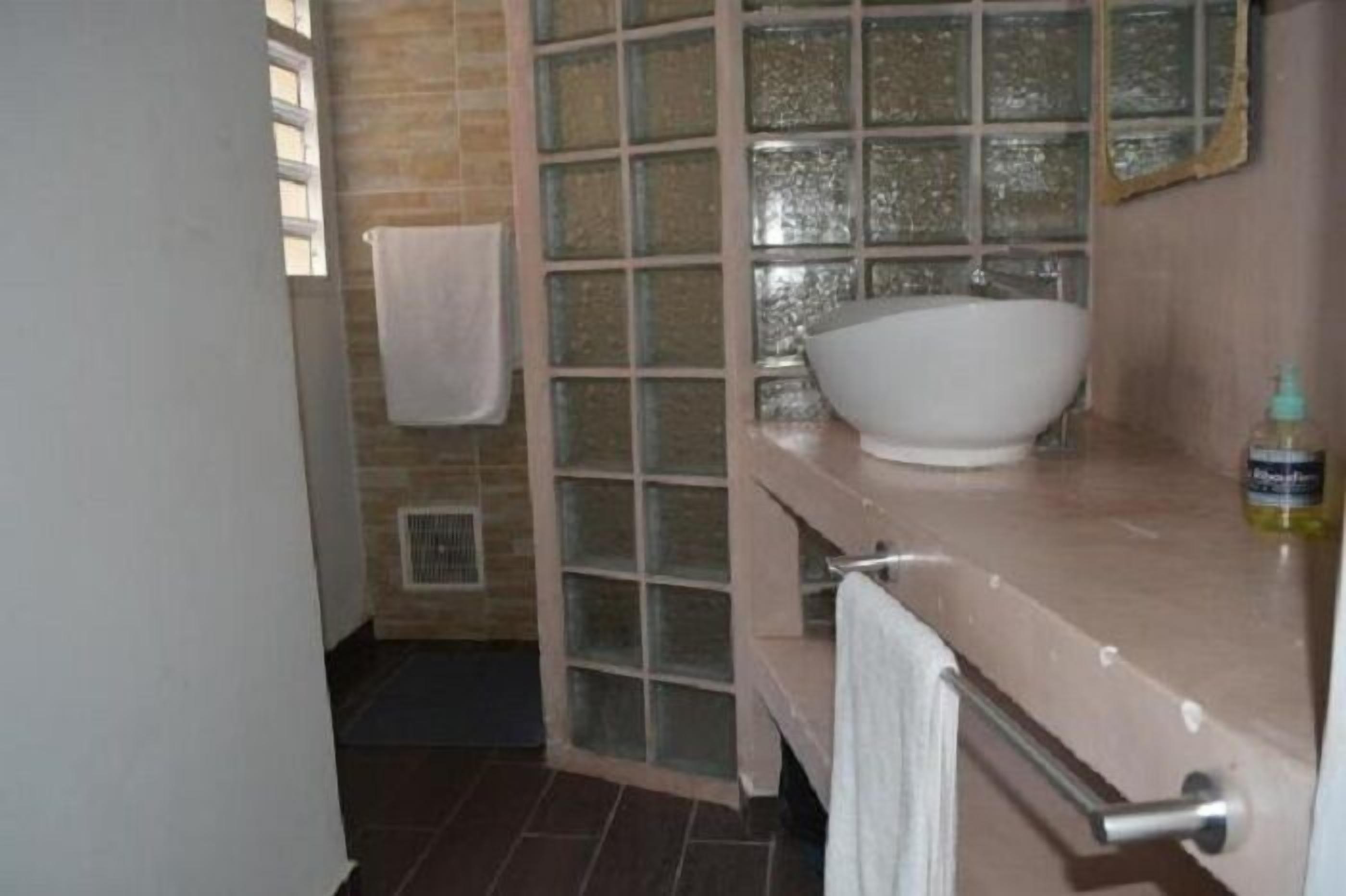 A bathroom with a glass shower enclosure, a white sink, and a towel rack.