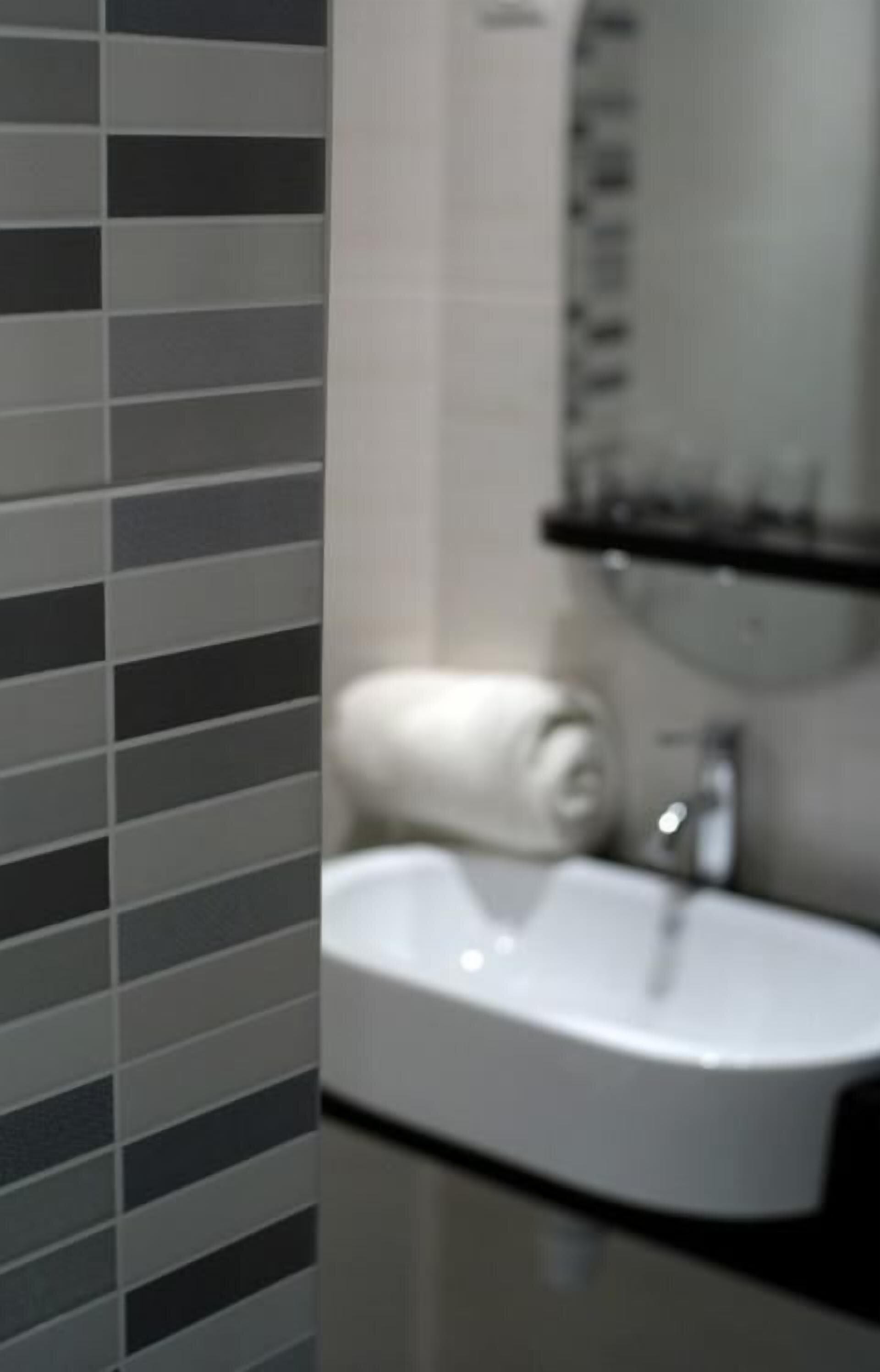 A bathroom with a white sink, a towel on the counter, and a mirror above the sink.