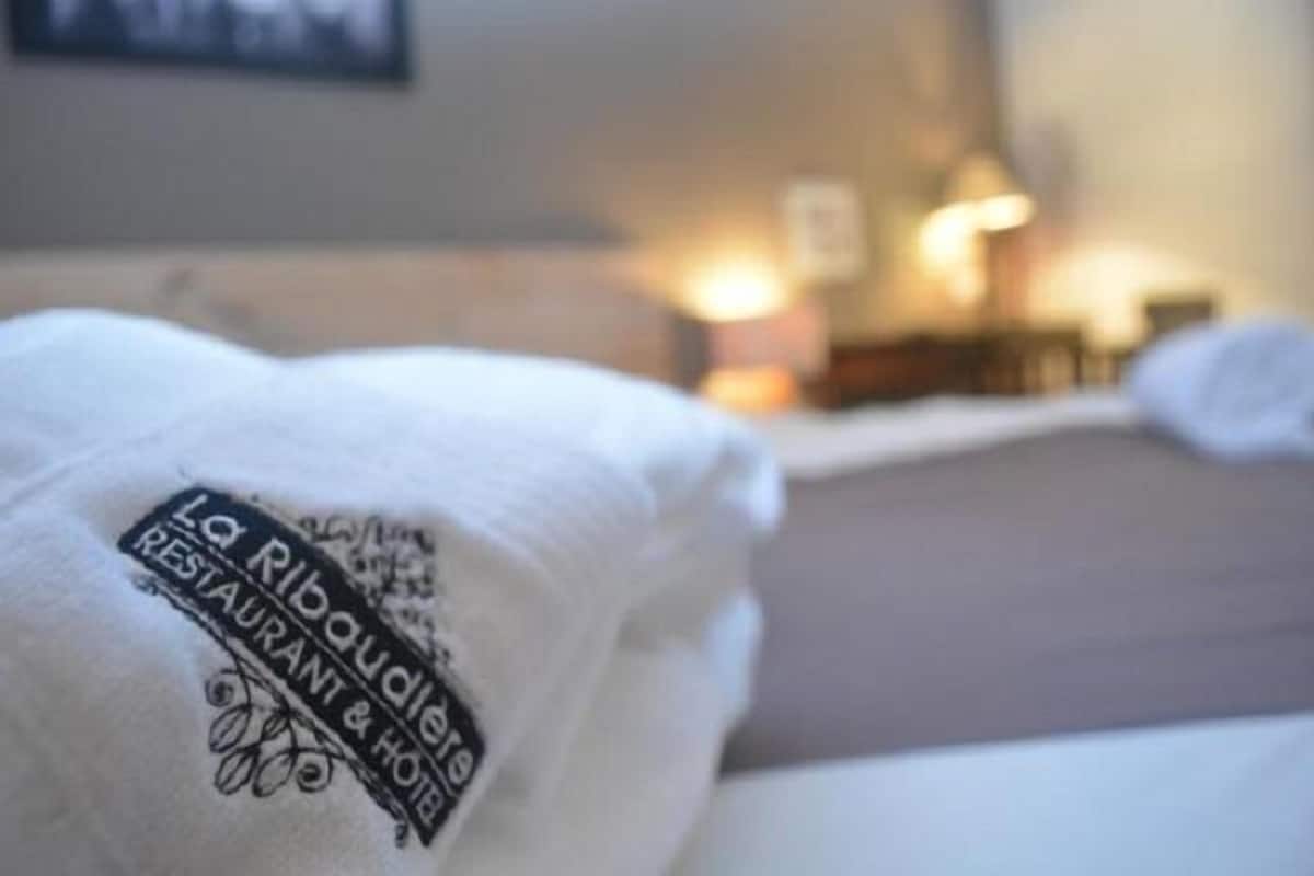 A hotel room with a bed and a pillow displaying the hotel's name.