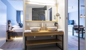 A modern bathroom with two sinks, a large mirror, and a shower area. - Residenz Hochalm (Saalbach-Hinterglemm)