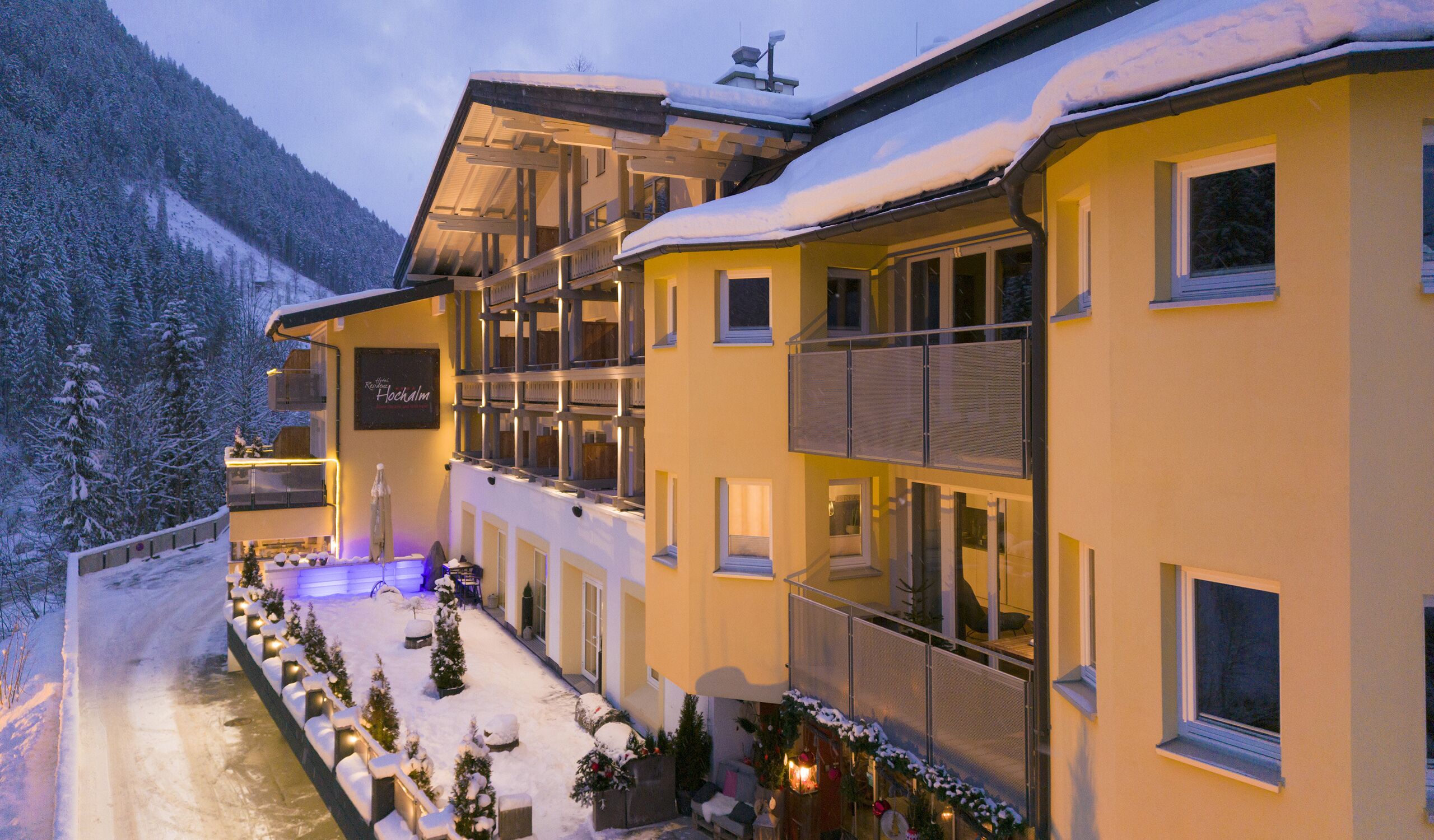 Un hôtel à plusieurs étages doté de balcons, dont la façade est recouverte de neige, et qui offre une vue sur les montagnes.