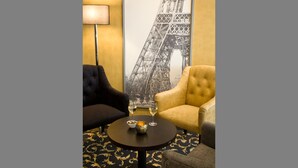 A room with a large Eiffel Tower poster, two armchairs, a small table with a vase and two glasses of wine. - Gildors Hotel Atmosphère (Düsseldorf)