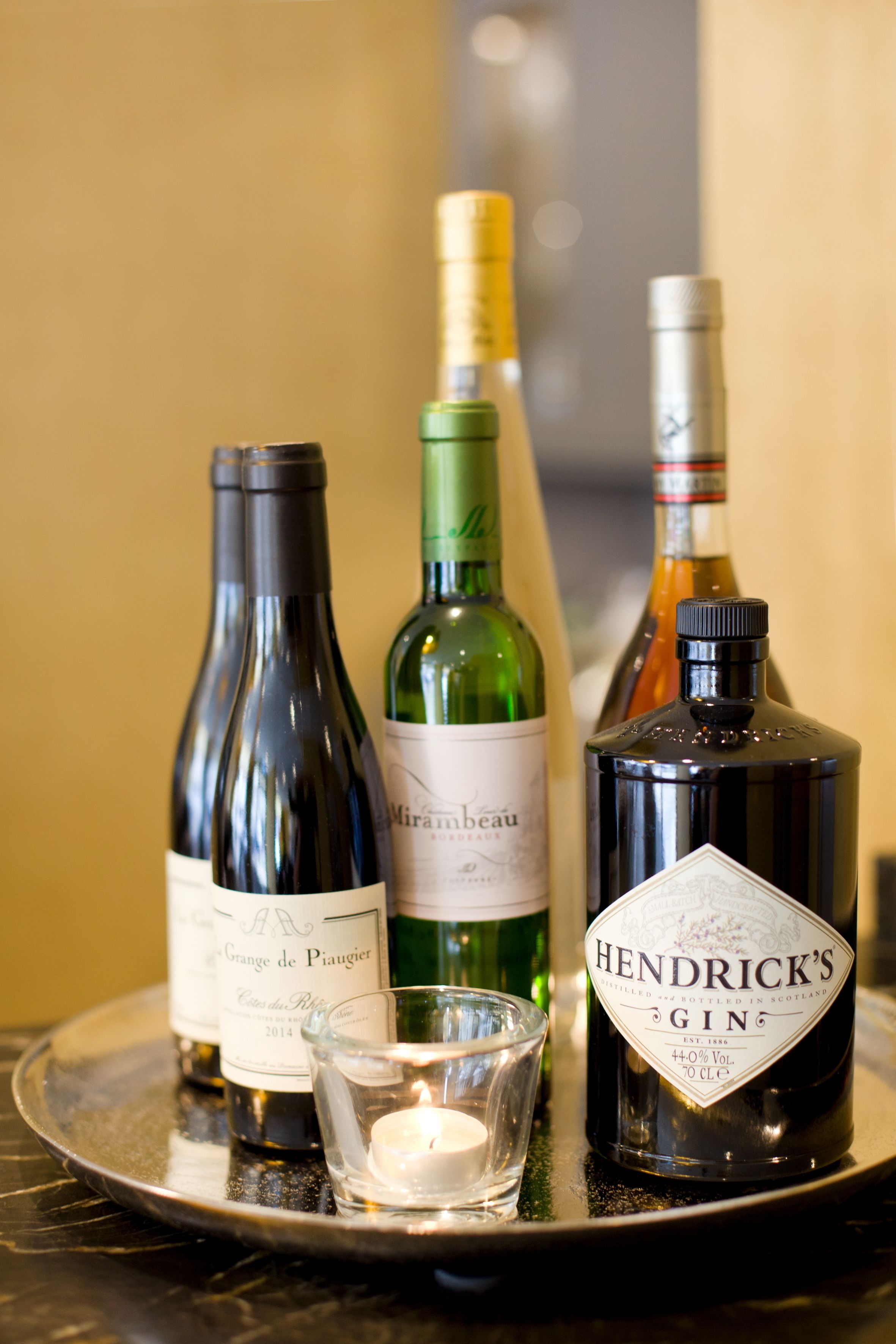 A tray with several bottles of wine and a candle.